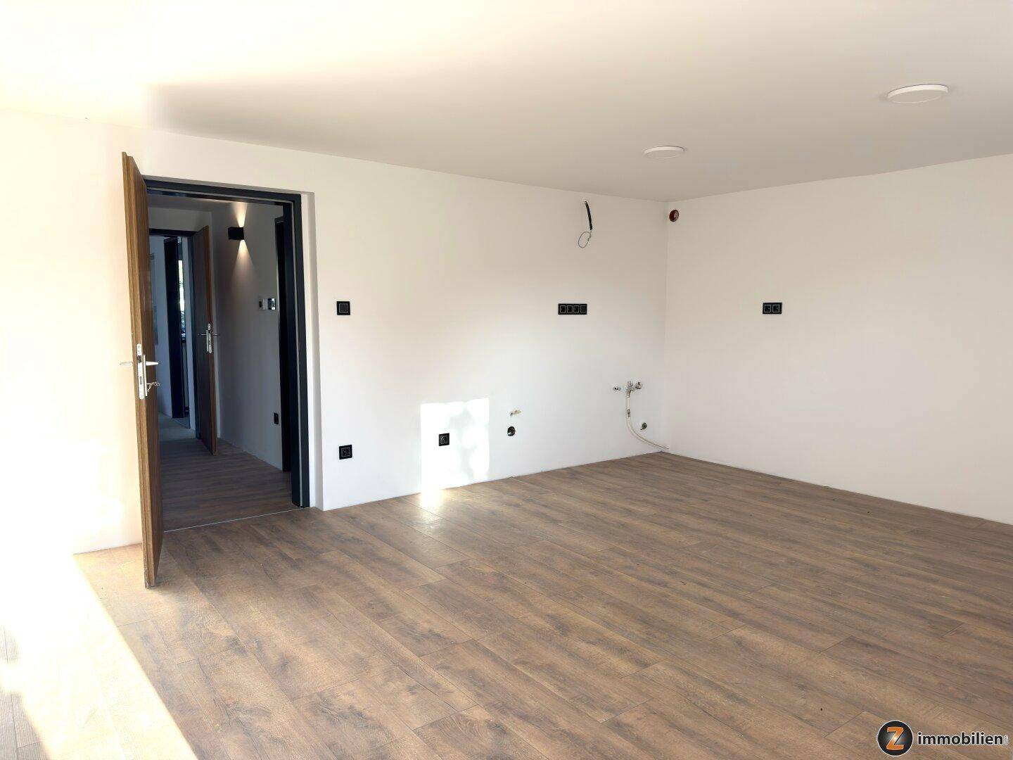 Unmöbliertes Zimmer mit Laminatboden und Zugang zu weiteren Räumen, ideal als Schlafzimmer.