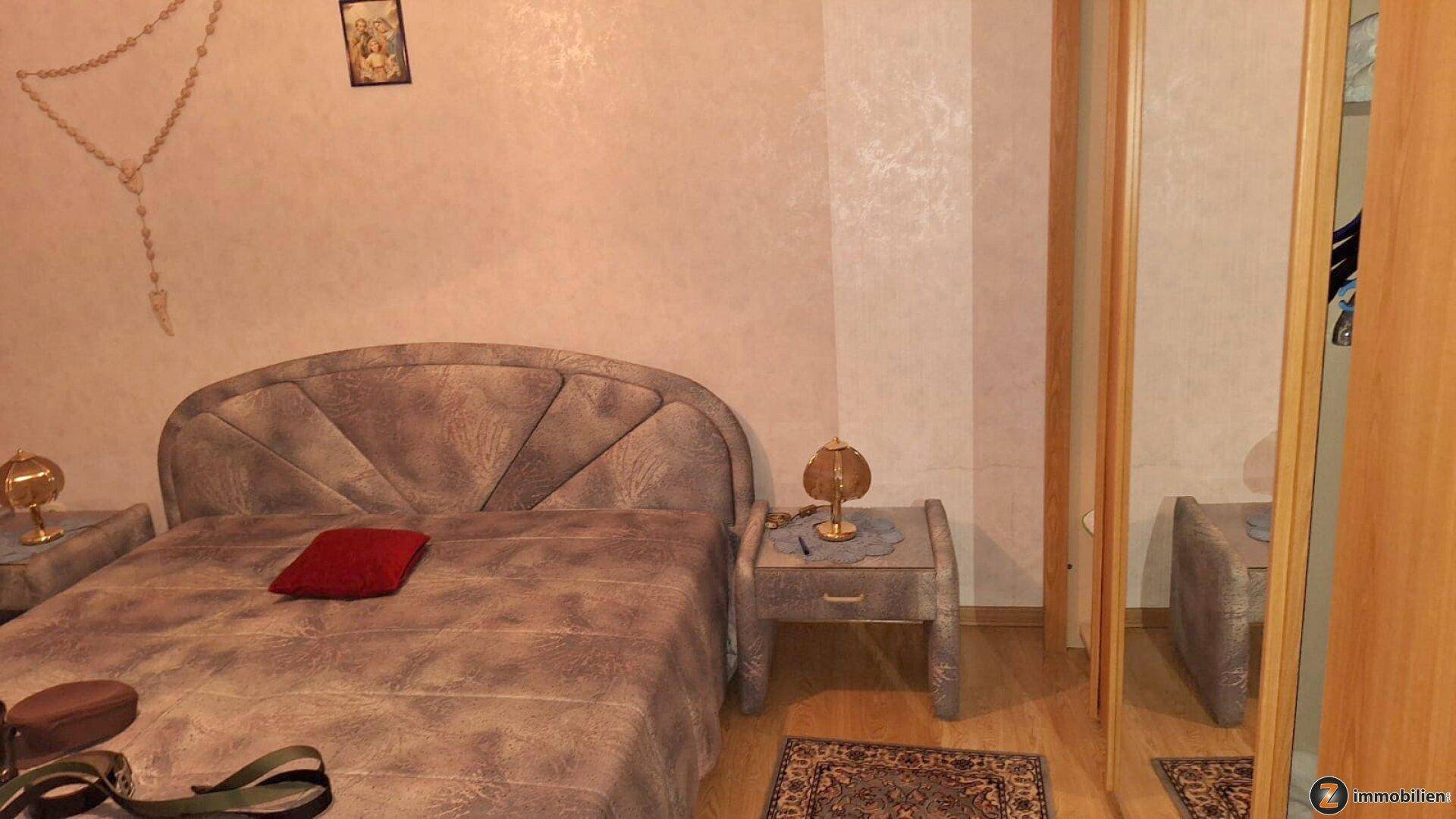 Schlafzimmer mit Doppelbett, Nachttischen und großem Spiegelschrank, in traditionellem Stil.