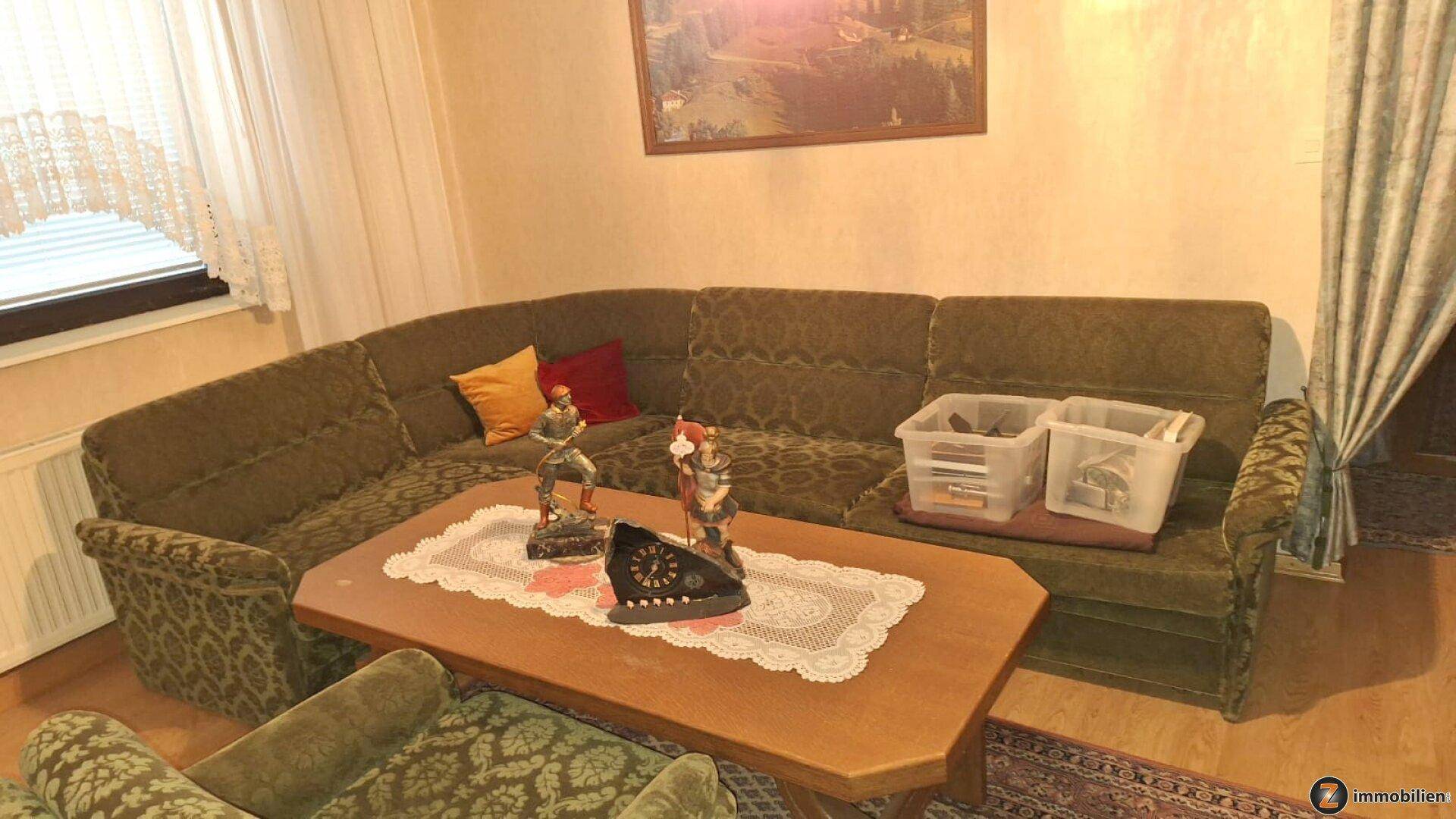 Geräumiges Wohnzimmer mit großer Eckcouch, Holztisch und traditioneller, gemütlicher Einrichtung.