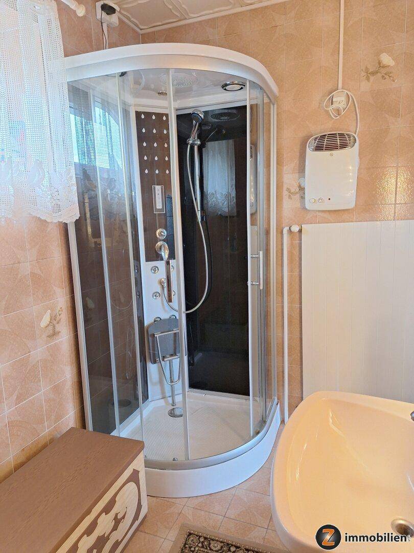 Badezimmer mit Duschkabine, Waschbecken und rosa Fliesen im Stil der 80er Jahre.