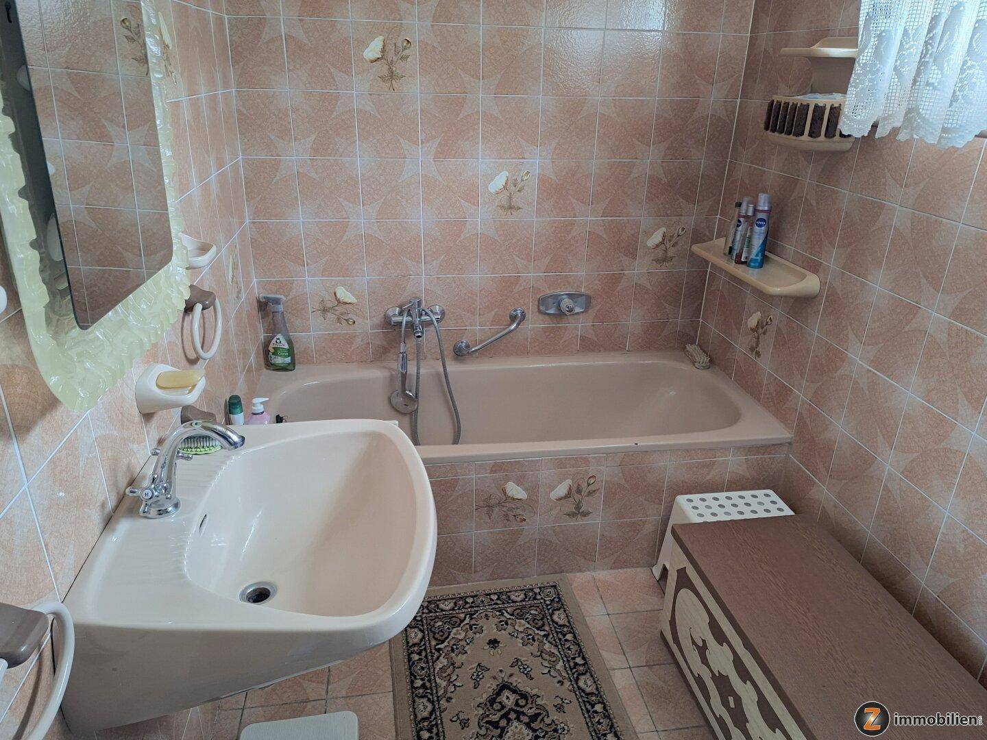 Badezimmer mit Badewanne, Waschbecken und rosa Fliesen im traditionellen Stil.
