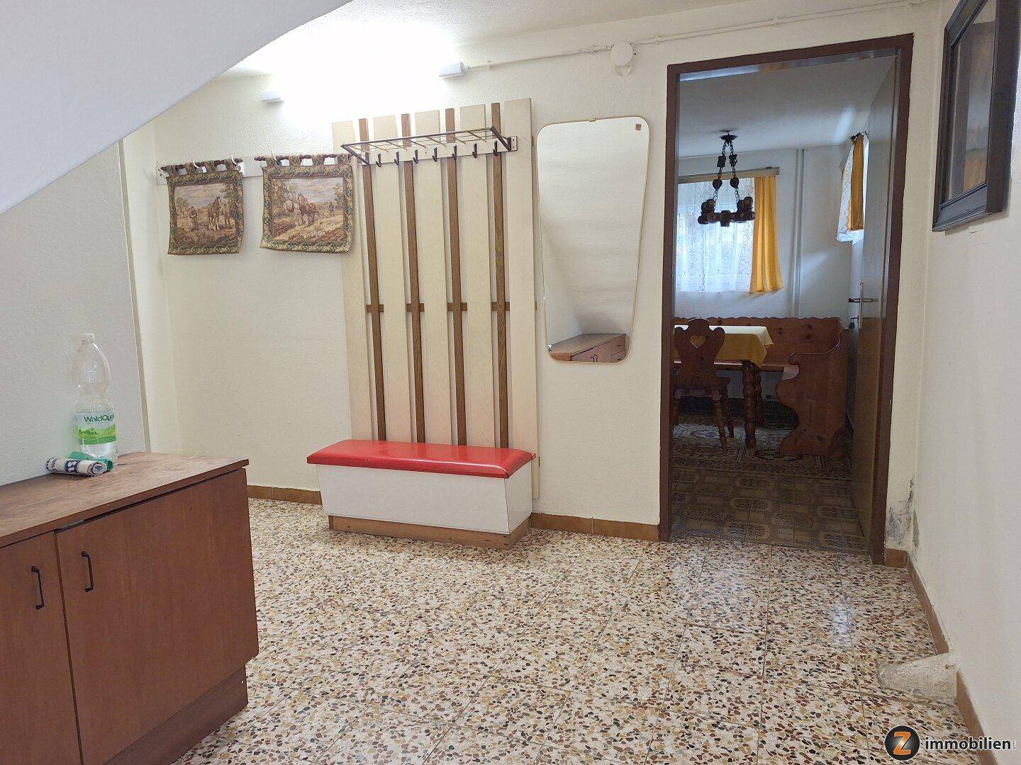 Flur im Dachgeschoss mit Garderobe und Terrazzoboden, der zu weiteren Räumen führt.