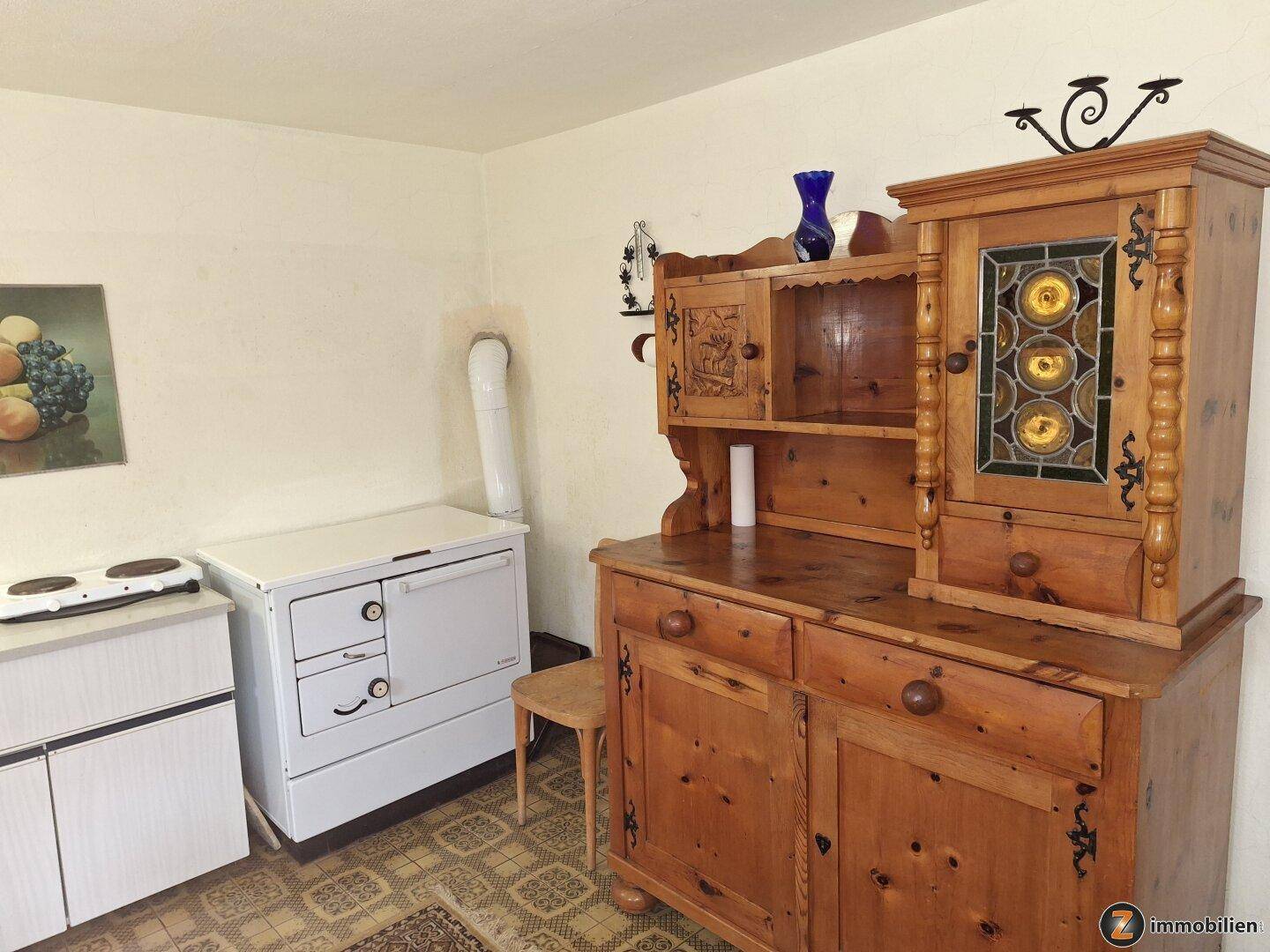 Traditionelle Küchenzeile mit Holzschrank, Ofen und gemusterten Bodenfliesen.