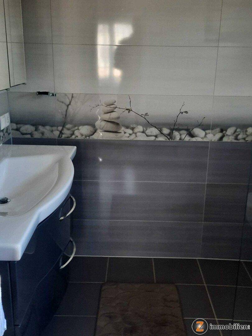 Modernes Badezimmer mit Einzelwaschbecken und dekorativen Steinmotiven an den Wänden.