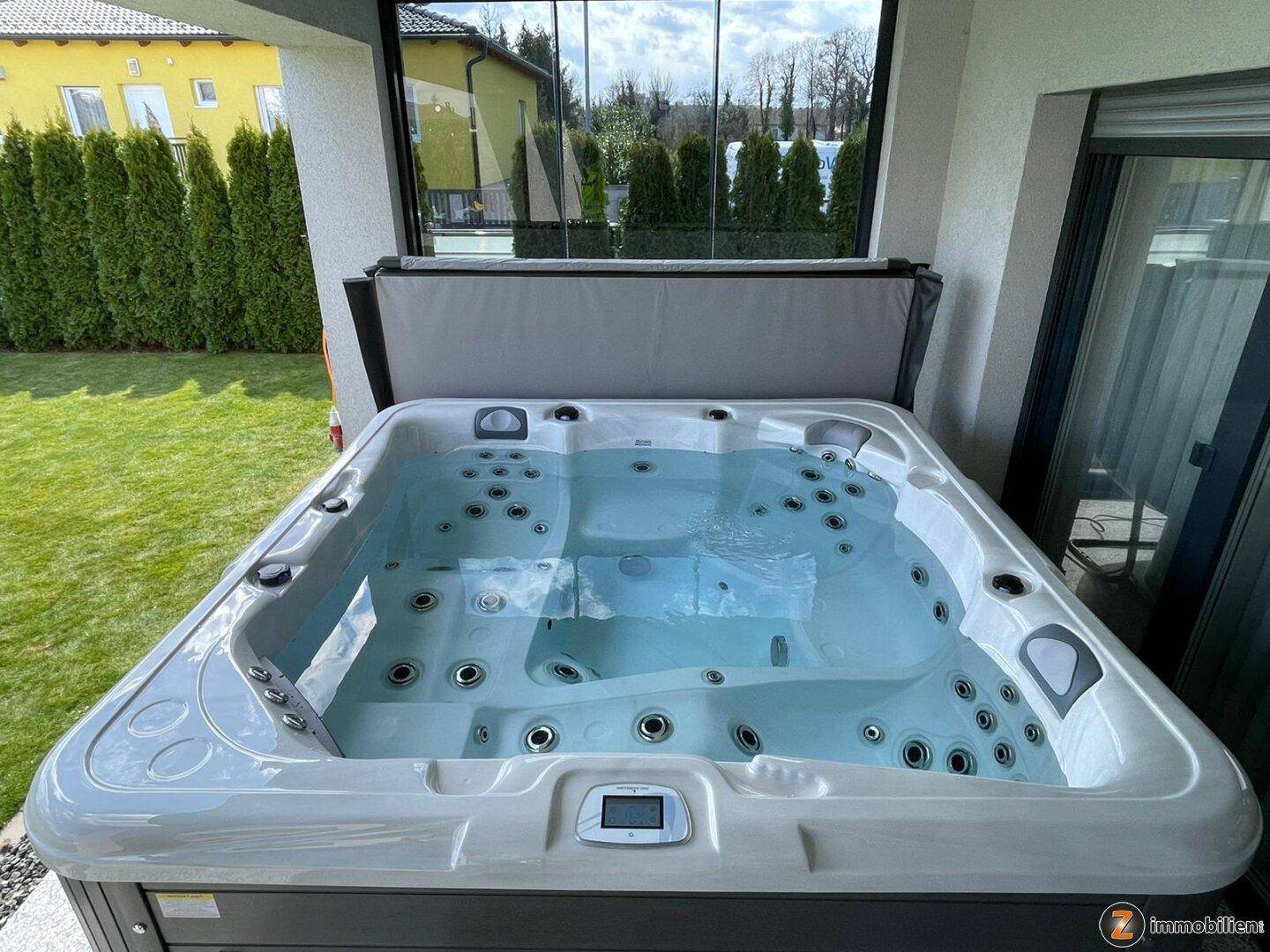 Moderner Whirlpool auf der Terrasse mit Blick auf den gepflegten Garten und die Umgebung.