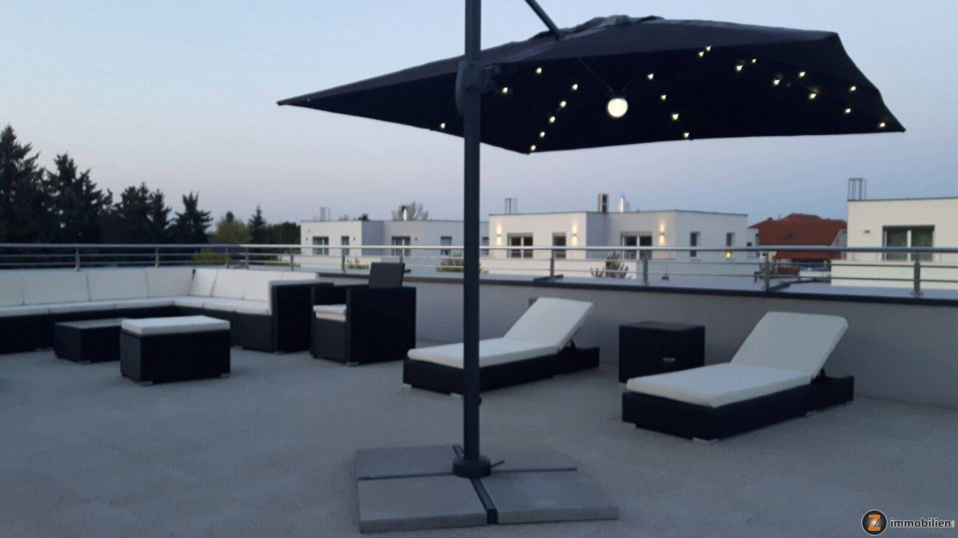 Geräumige Dachterrasse mit Lounge-Möbeln und Sonnenliegen, ideal für Entspannung im Freien.