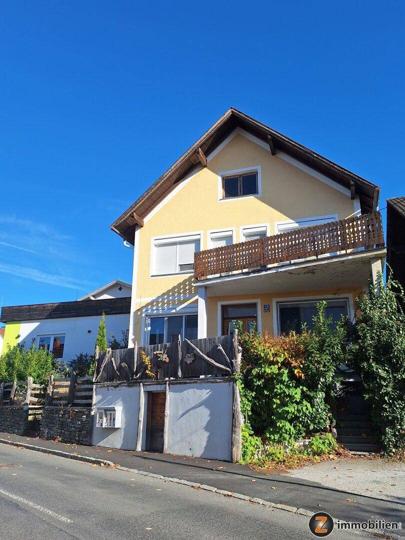 Traditionelles gelbes Haus mit Balkon und Rollläden, direkt an einer ruhigen Straße gelegen.