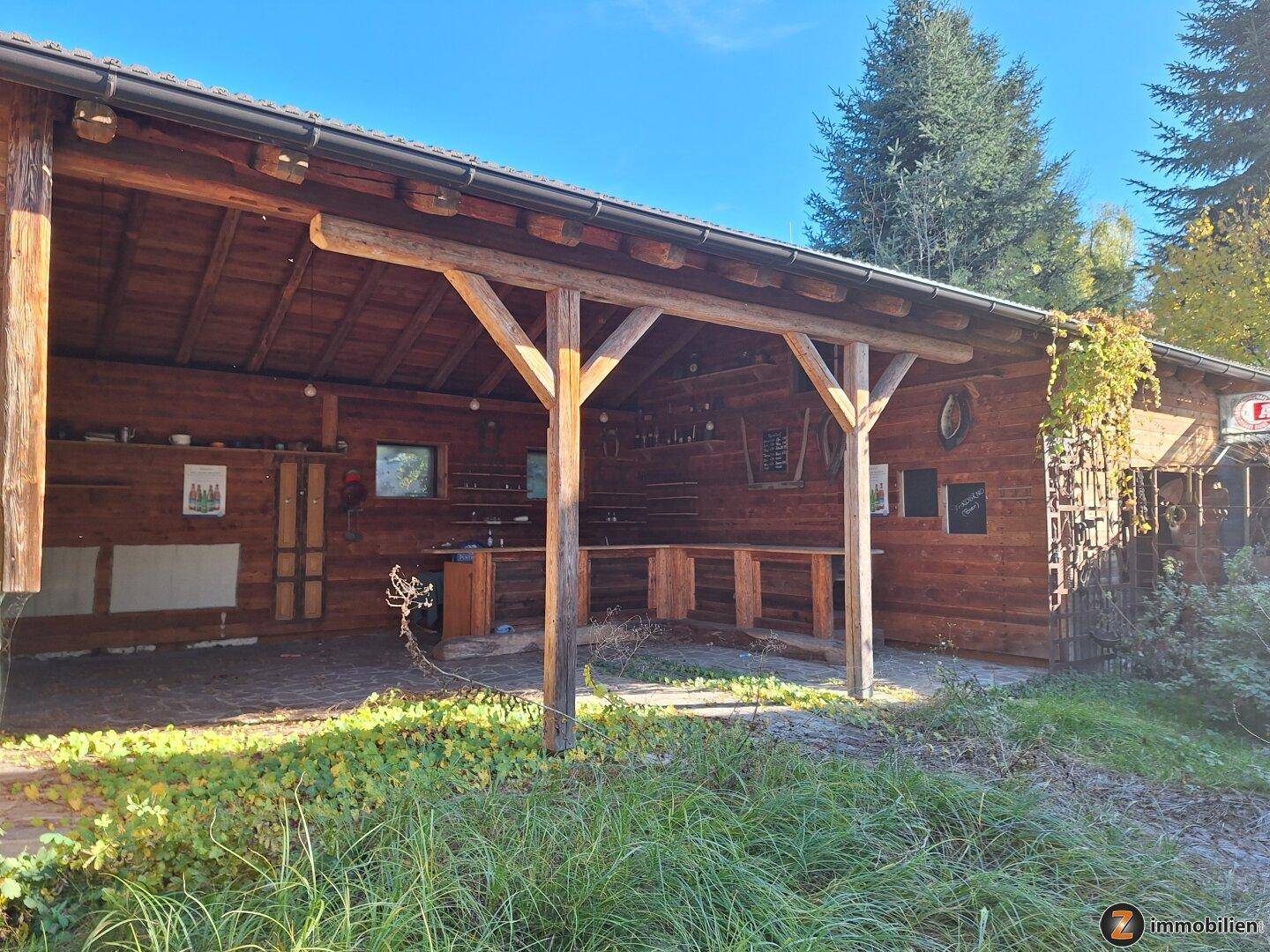 Rustikaler überdachter Außenbereich aus Holz, ideal für gesellige Stunden im Grünen.