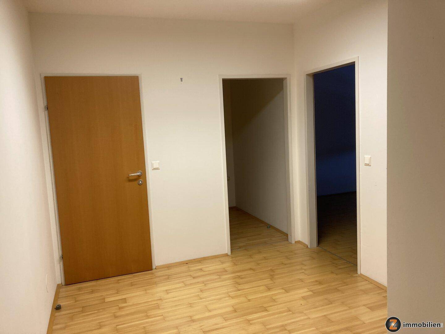Flur mit hellem Holzfußboden und mehreren Türen, die zu verschiedenen Räumen führen.