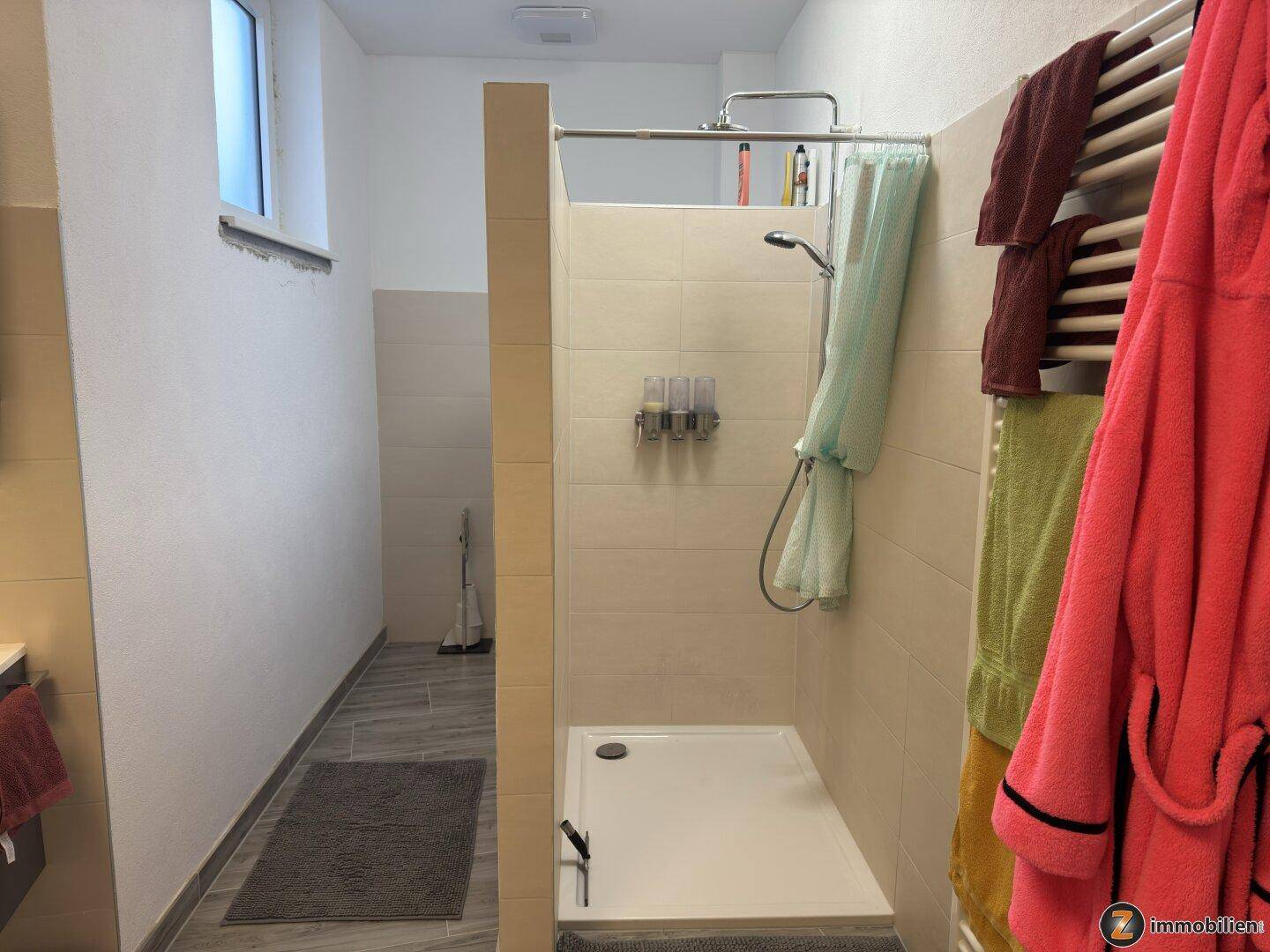 Helle begehbare Dusche im modernen Badezimmer mit Fliesen und Fenster für Tageslicht.