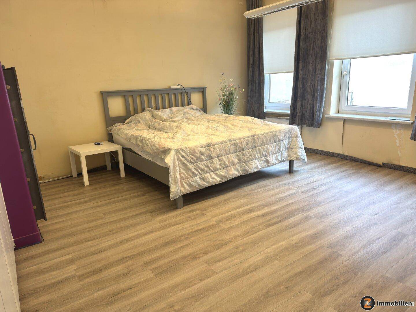 Geräumiges Schlafzimmer mit Laminatboden und großen Fenstern, bereit zur individuellen Gestaltung.