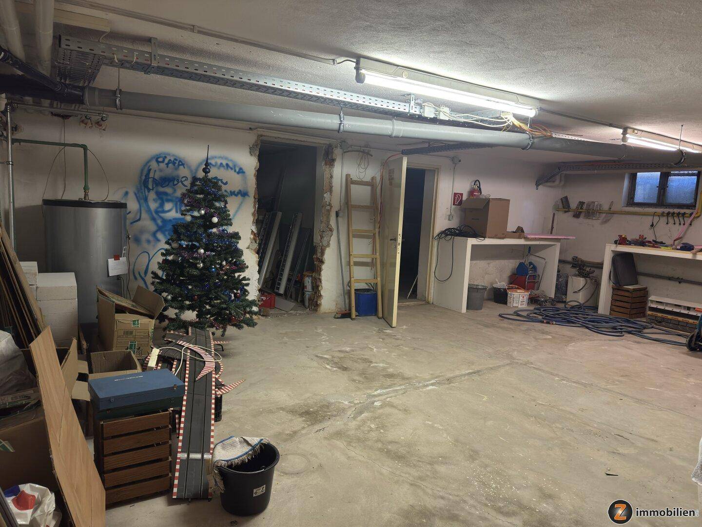 Unfertiger Kellerraum mit Betonboden, sichtbaren Leitungen und Lagerfläche.