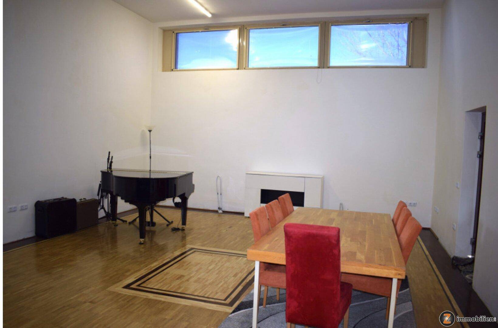 Geräumiger Wohn- und Essbereich mit Klavier, Holztisch und hohen Fenstern, ideal für gesellige Runden.