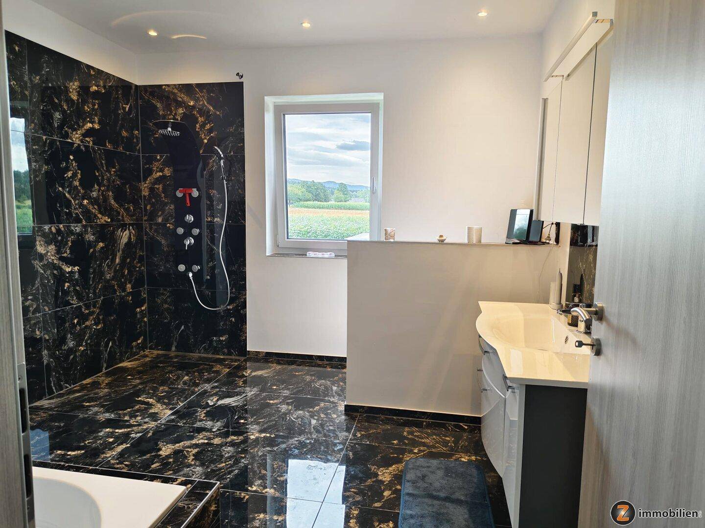 Geräumiges Badezimmer mit großer begehbarer Dusche und Fenster mit Weitblick.