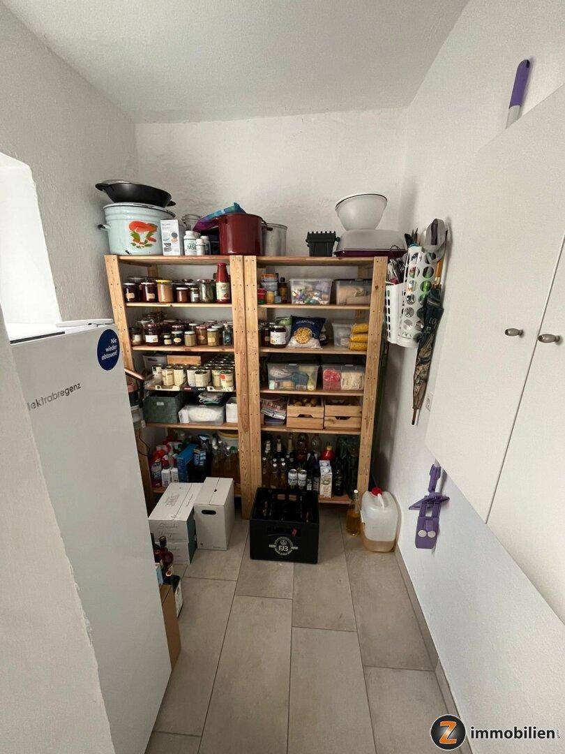 Gut gefüllte Speisekammer mit Holzregalen und zahlreichen Vorräten, ordentlich organisiert.