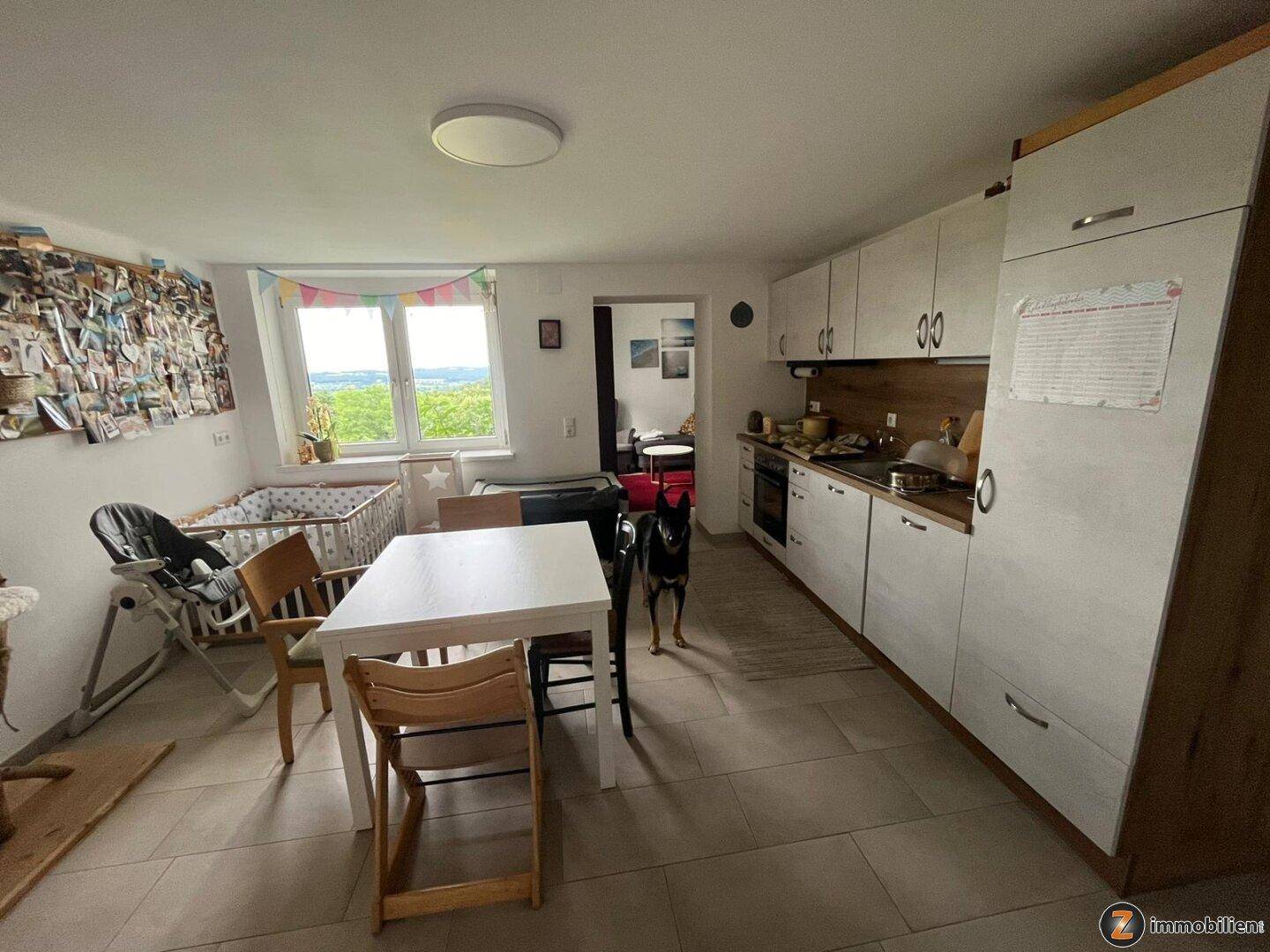 Funktionale Küche mit weißen Schränken, Holzarbeitsplatte und Essbereich mit Blick ins Grüne.