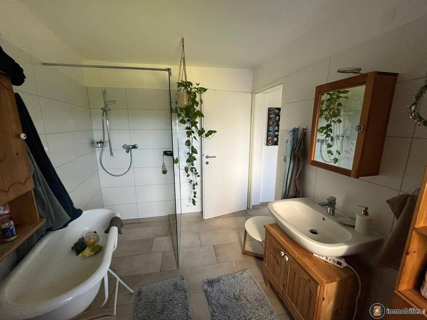 Modernes Badezimmer mit Fliesenboden, freistehender Badewanne, Dusche und Einzelwaschbecken.
