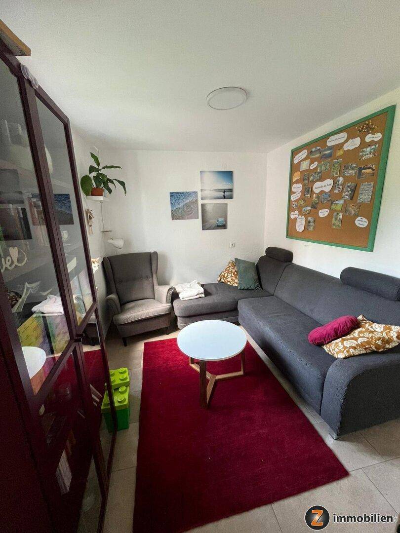 Gemütliches Wohnzimmer mit großem Ecksofa, rotem Teppich und modernem Couchtisch.