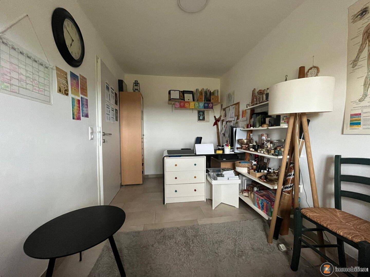 Helles Arbeitszimmer mit Fliesenboden, Schreibtisch und Regalen, gut organisiert.