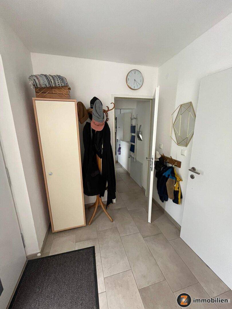 Heller Flur mit Fliesenboden, Garderobe und einem Spiegel, der den Raum erweitert.