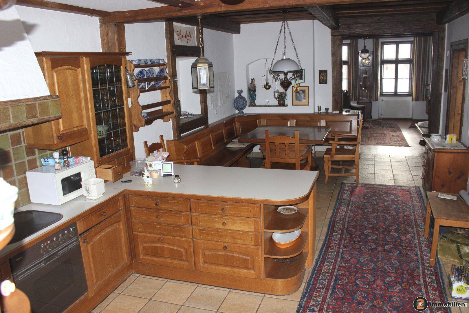 Traditionelle Holzküche mit Essbereich, Fliesenboden und sichtbaren Deckenbalken.