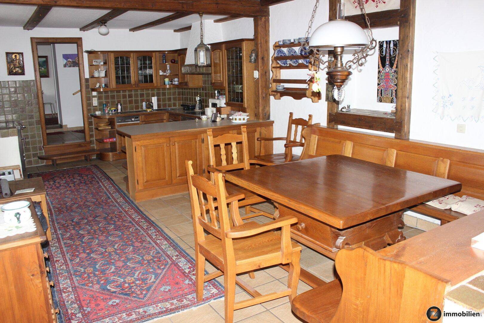 Geräumige Holzküche mit großem Esstisch und traditionellen Elementen, offen zum Wohnbereich.