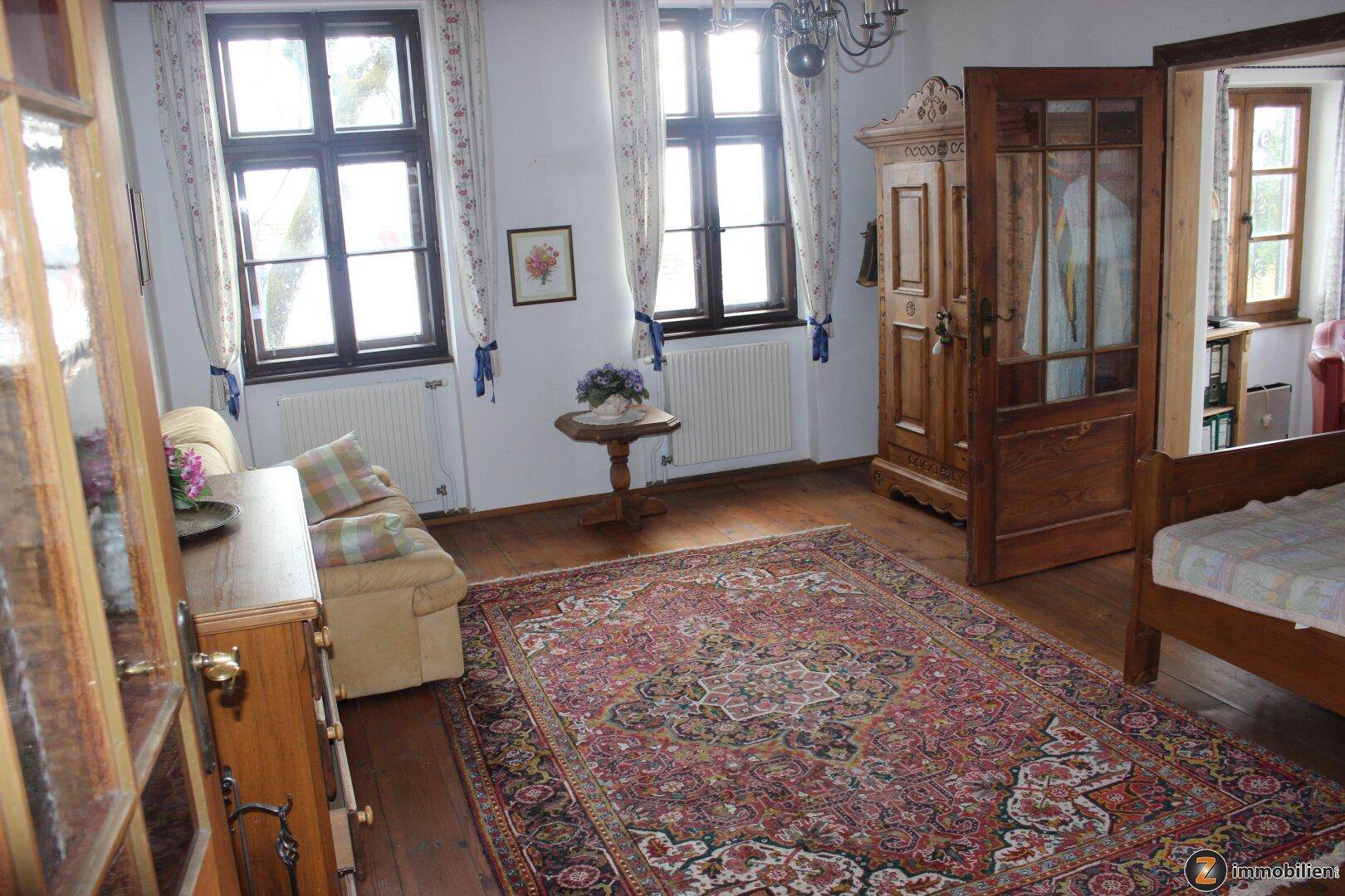 Schlafzimmer im traditionellen Stil mit Holzboden, antiken Möbeln und zwei Fenstern.