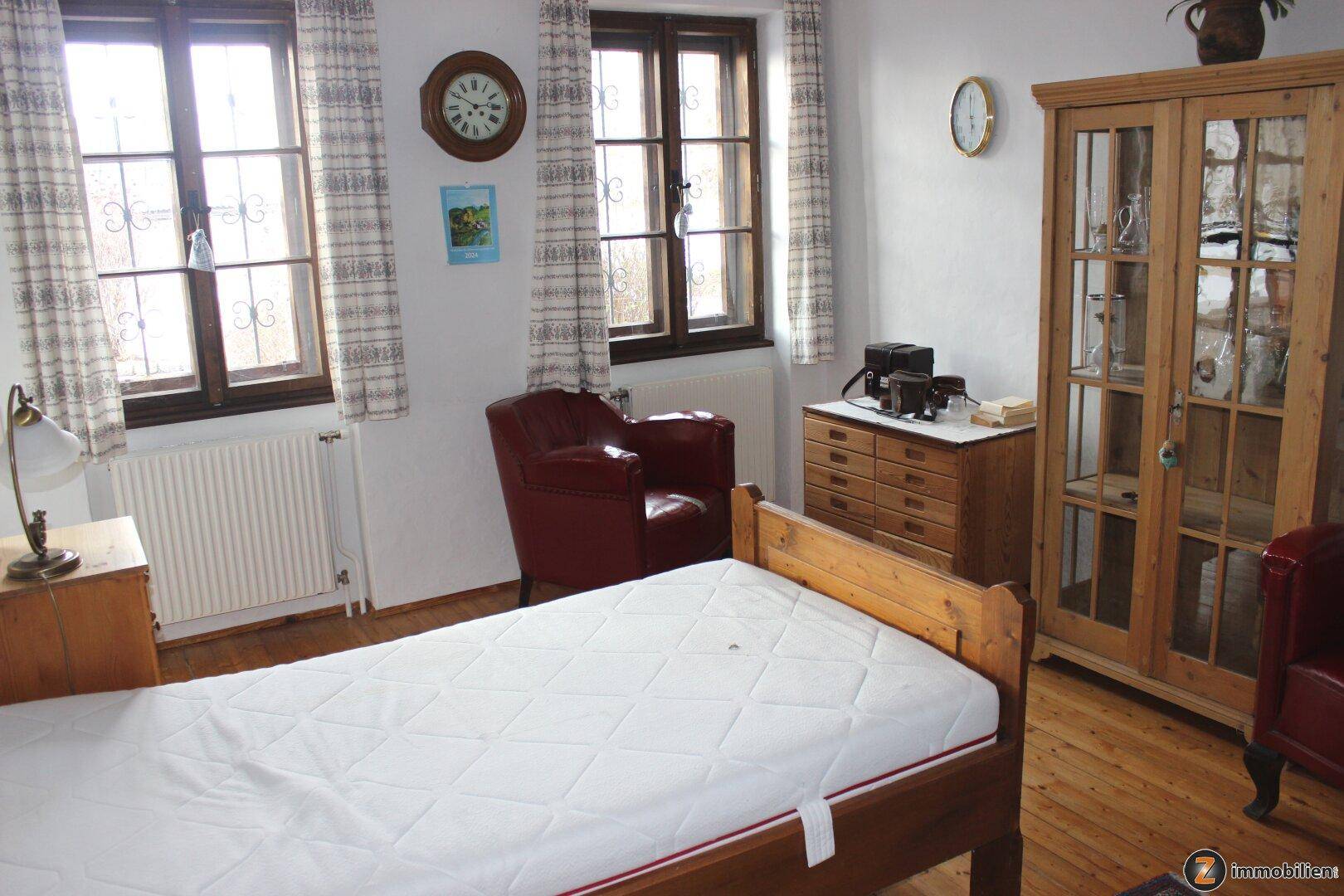 Schlafzimmer mit Holzboden, Einzelbett und traditionellen Holzmöbeln.