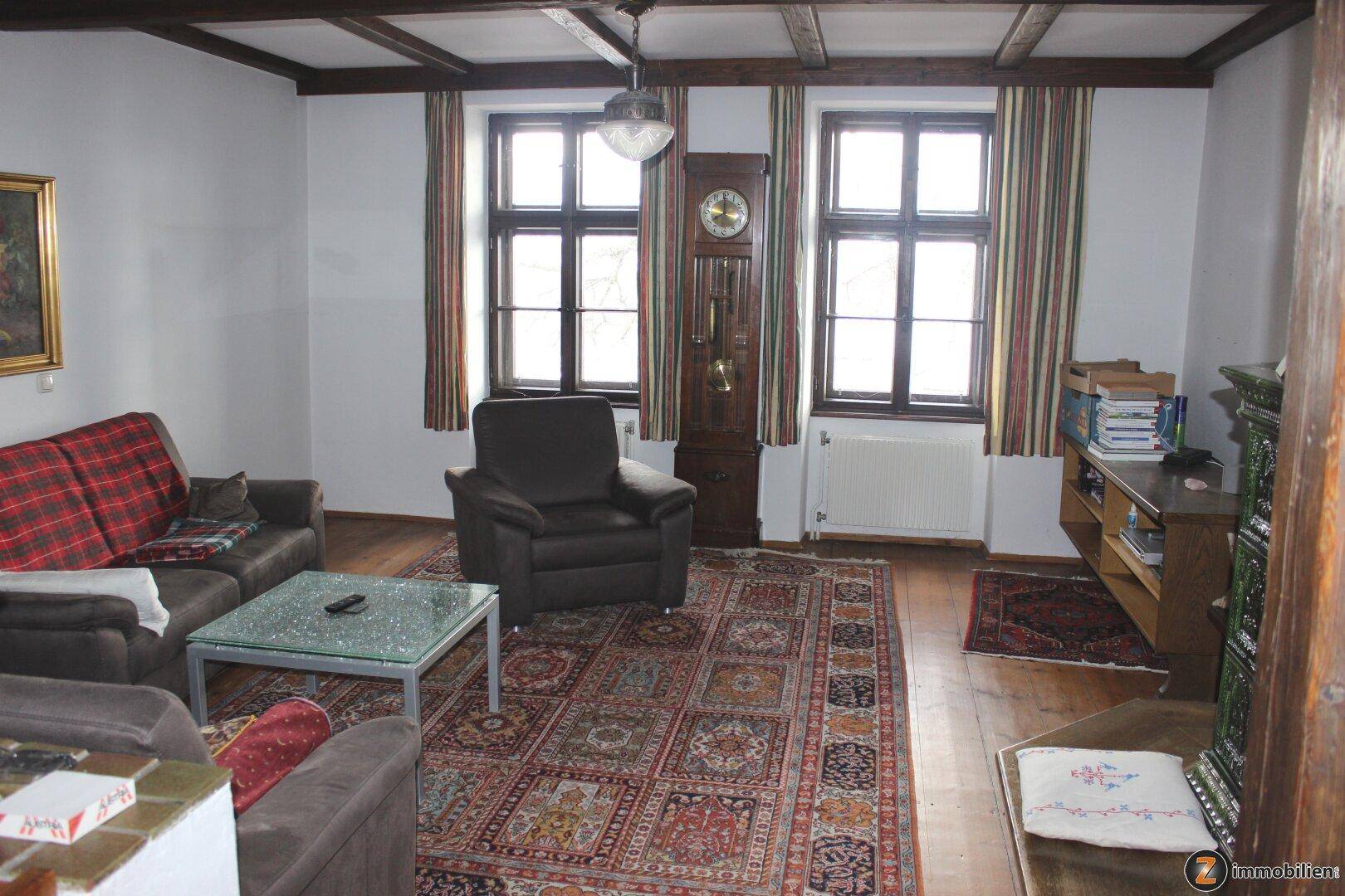 Wohnzimmer mit Holzboden, gemütlichen Sofas und traditionellem Teppich.