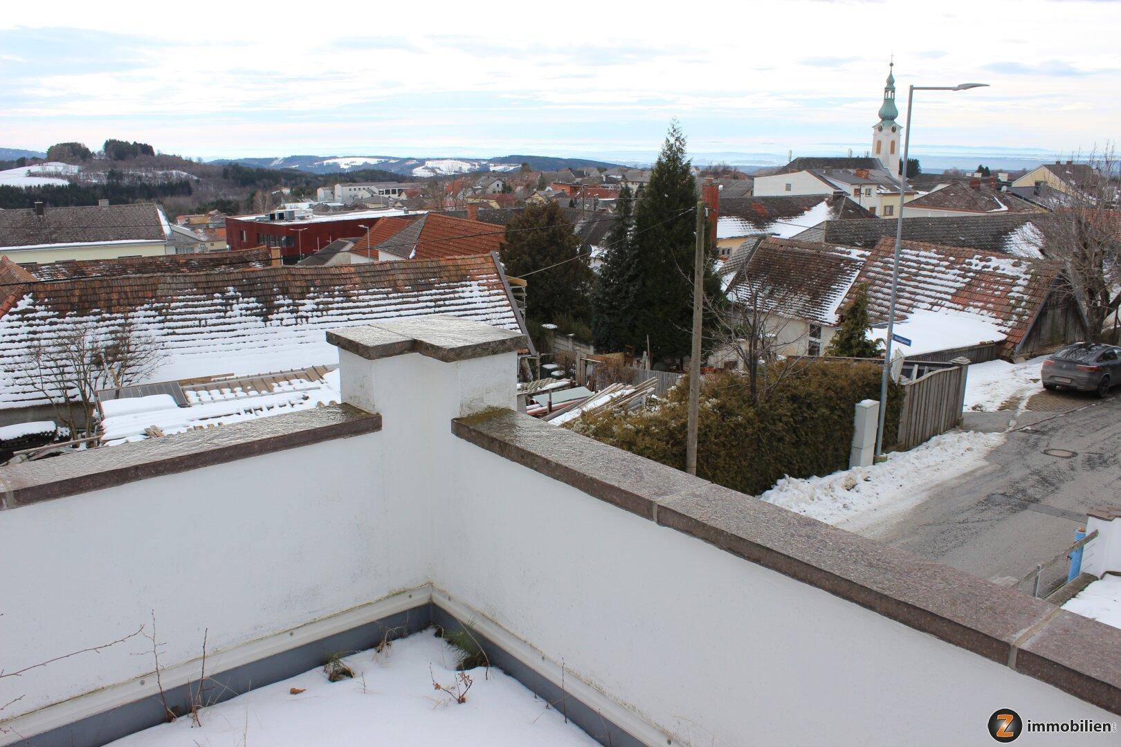 Weitläufiger Blick über die verschneite Stadt und die umliegende Hügellandschaft.