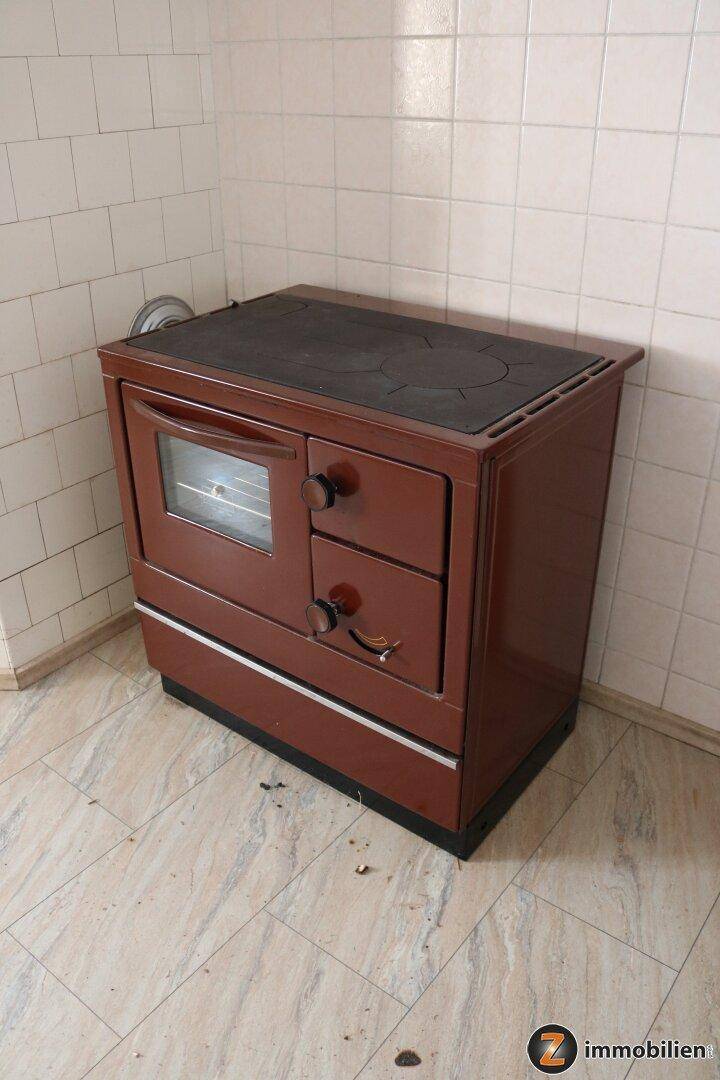 Nahaufnahme eines traditionellen, braunen Holzofens mit Kochplatte und Backfach.