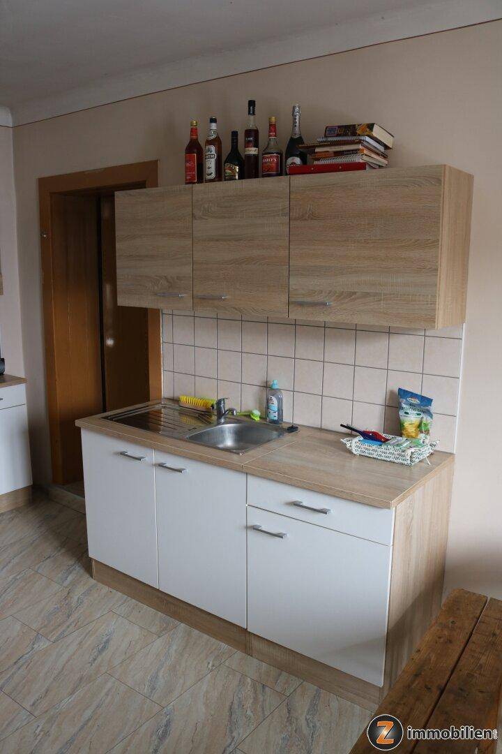 Detailansicht einer Küchenzeile mit Spülbecken, Holz-Arbeitsplatte und Oberschränken.