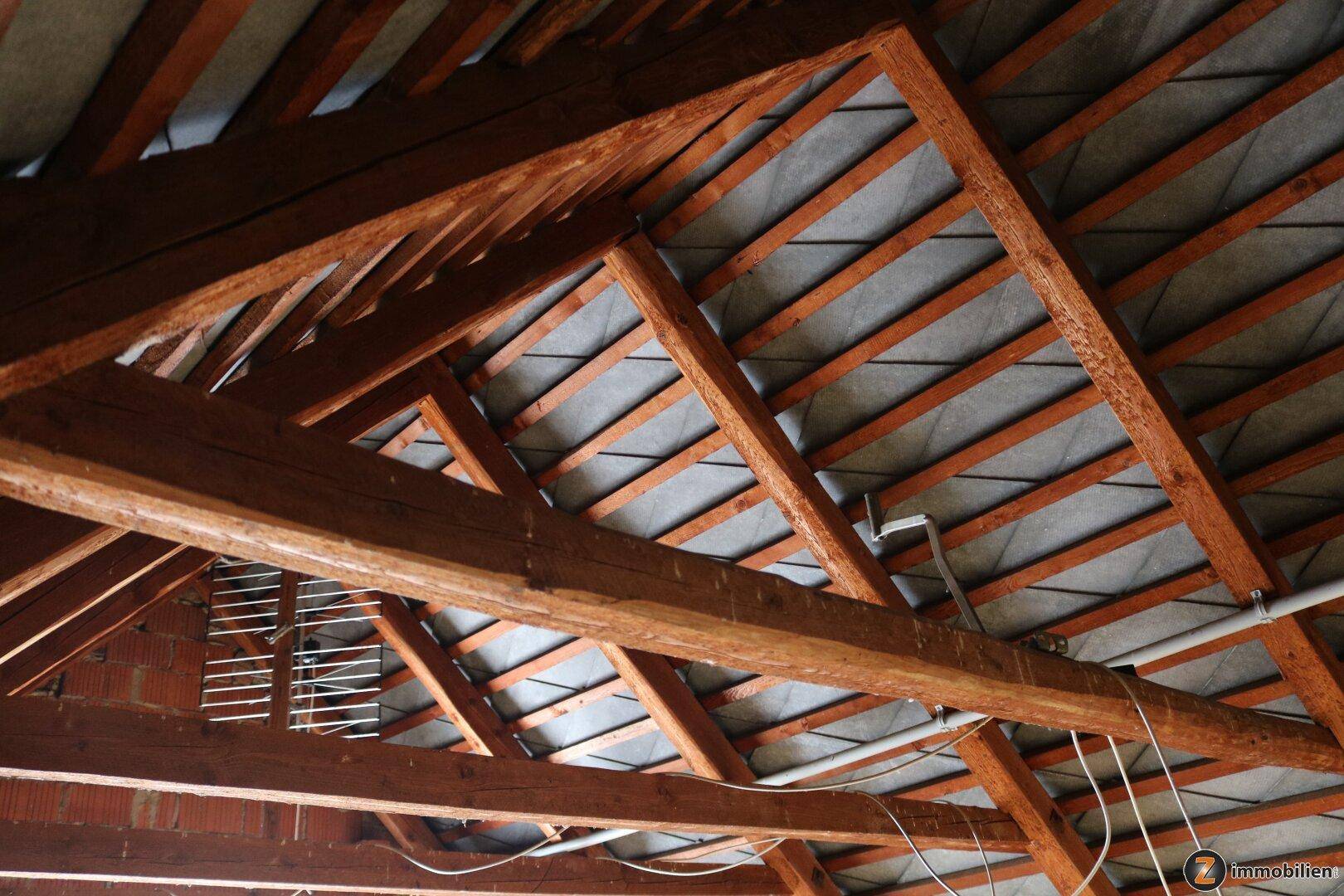Offener Dachstuhl mit sichtbaren Holzbalken und Dachkonstruktion, bereit für Ausbau.