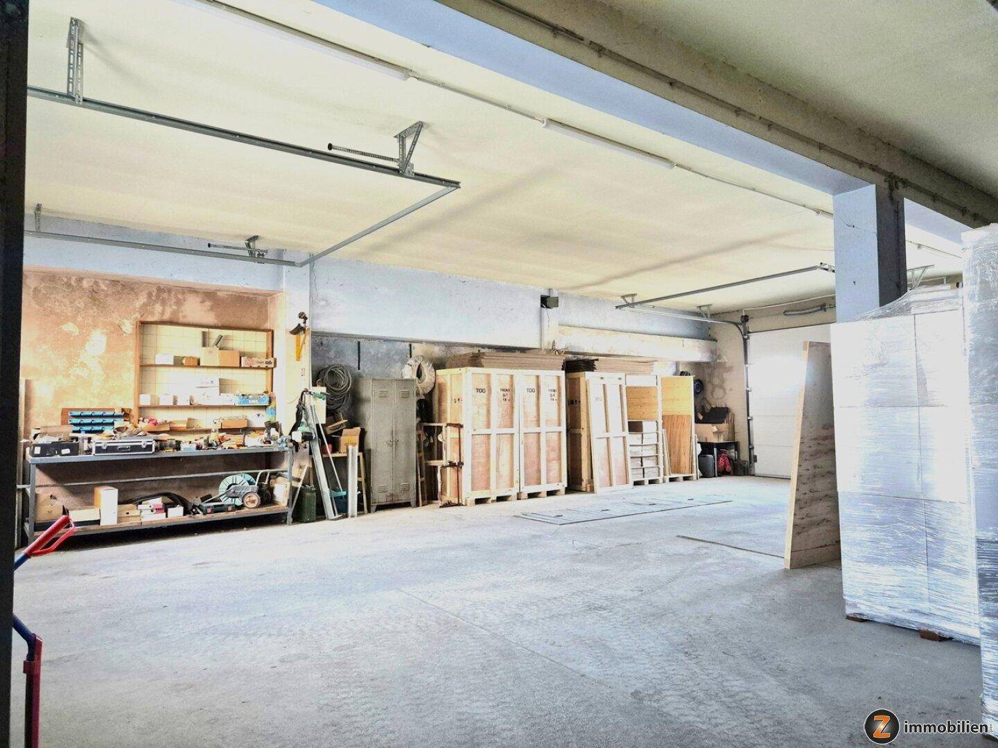 Große Lagerhalle mit Werkbank, Regalen und viel Platz für verschiedene Materialien.