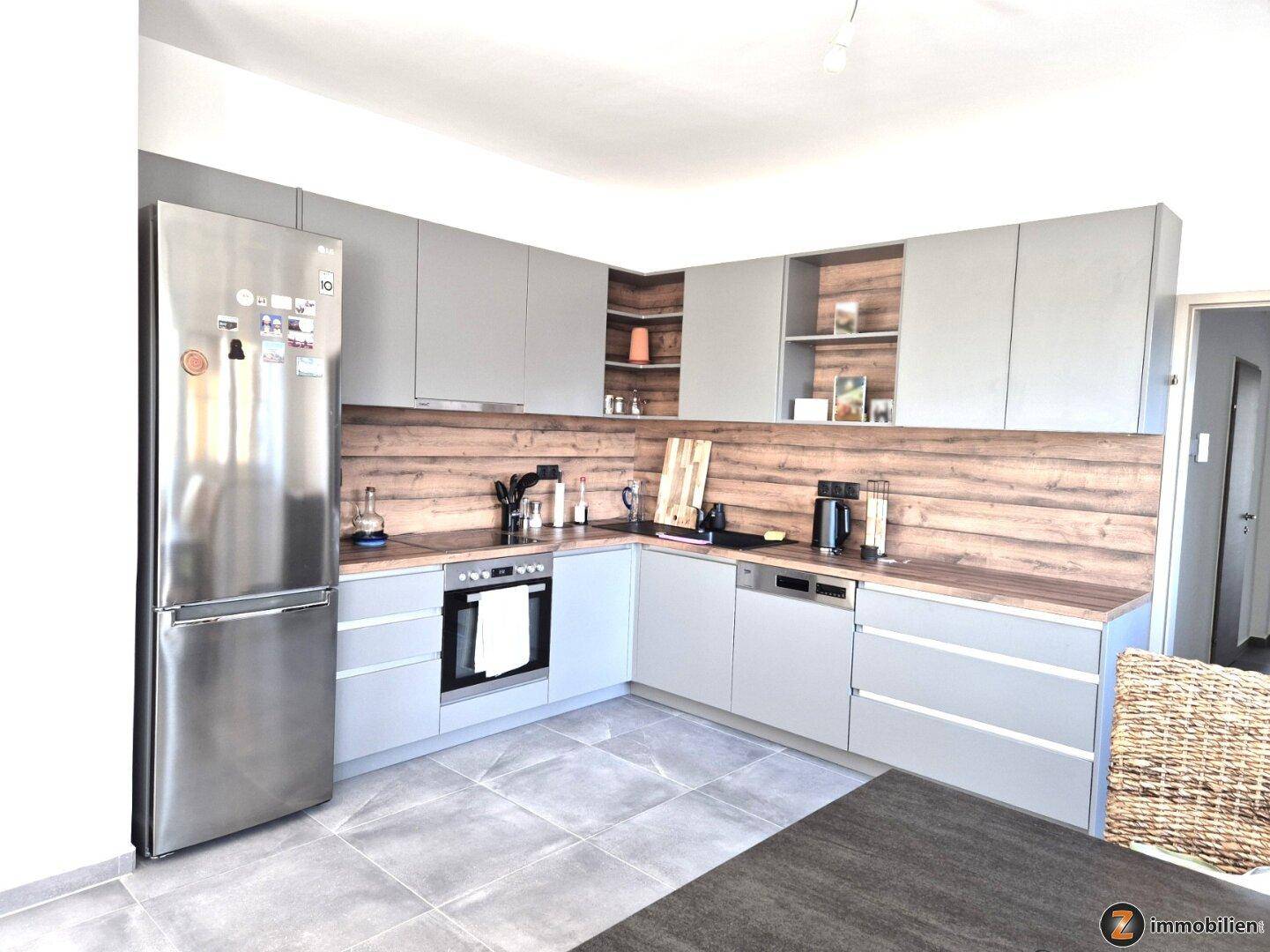 Moderne Einbauküche mit grauen Fronten, Holzoptik-Arbeitsplatte und integrierten Geräten.