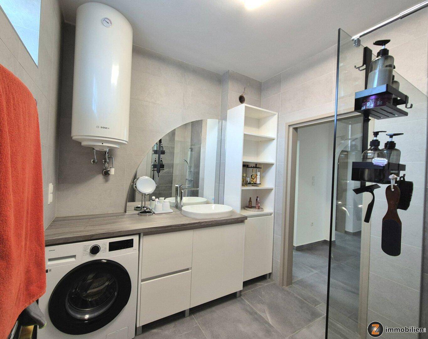 Modernes Badezimmer mit Dusche, Waschbecken, Waschmaschine und Warmwasserboiler.