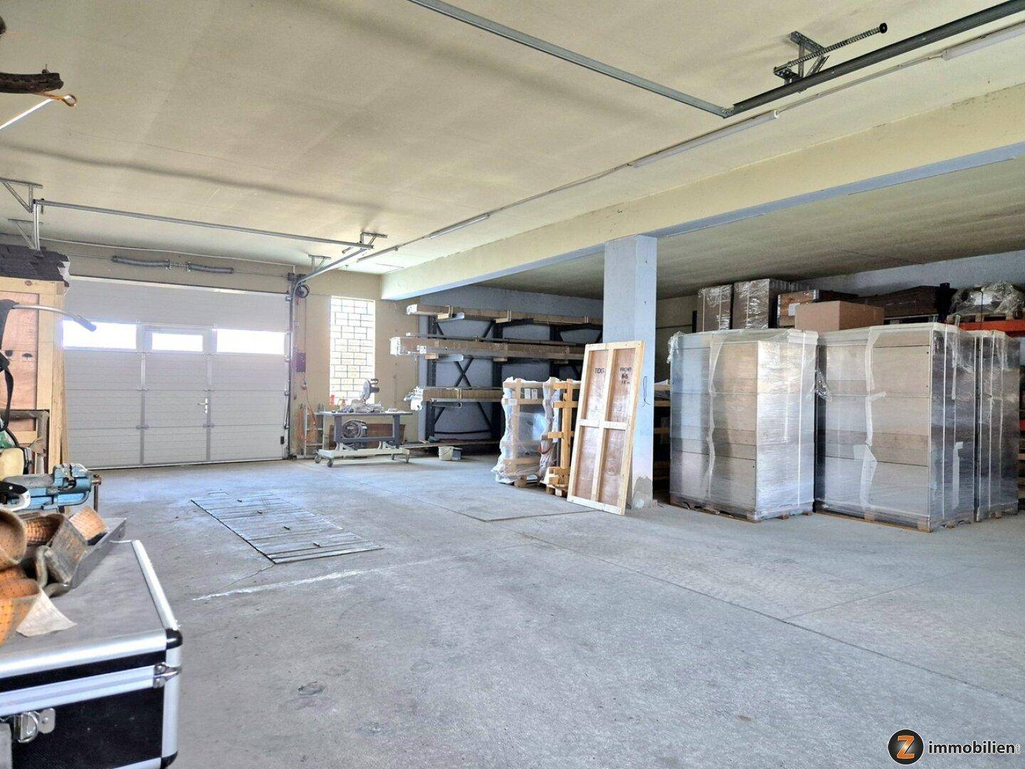 Geräumige Garage oder Lagerhalle mit Rolltor, Betonboden und hohen Decken.