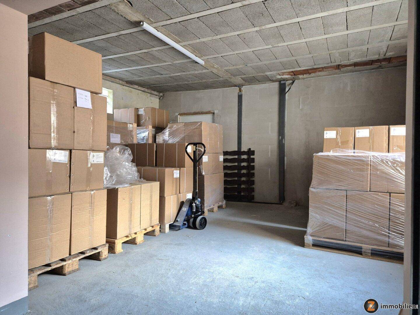 Lagerraum im Keller mit gestapelten Kartons auf Paletten und Betonboden.