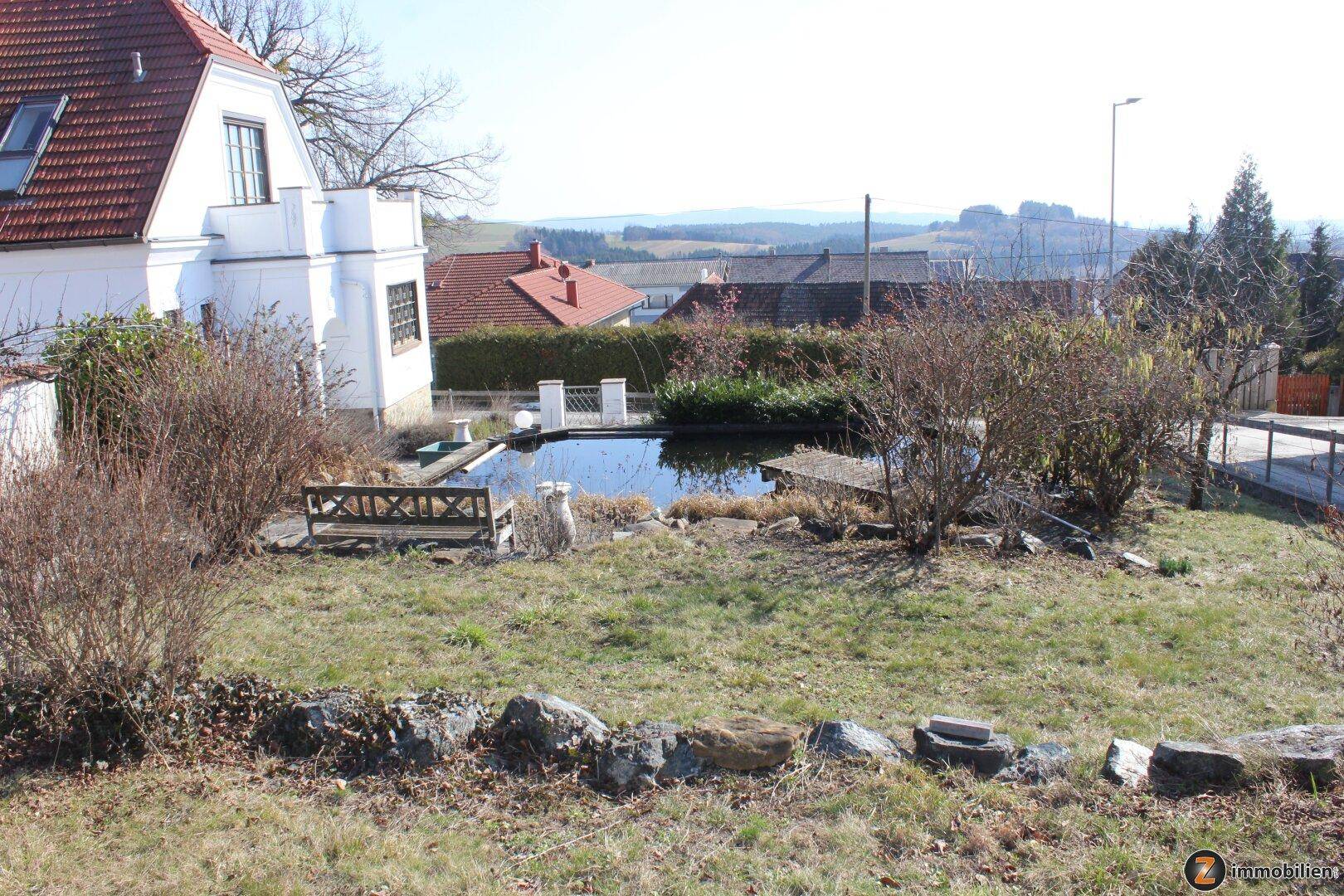 Gartenbereich mit Teichanlage, Sitzgelegenheiten und weitem Blick über die umliegende Landschaft.