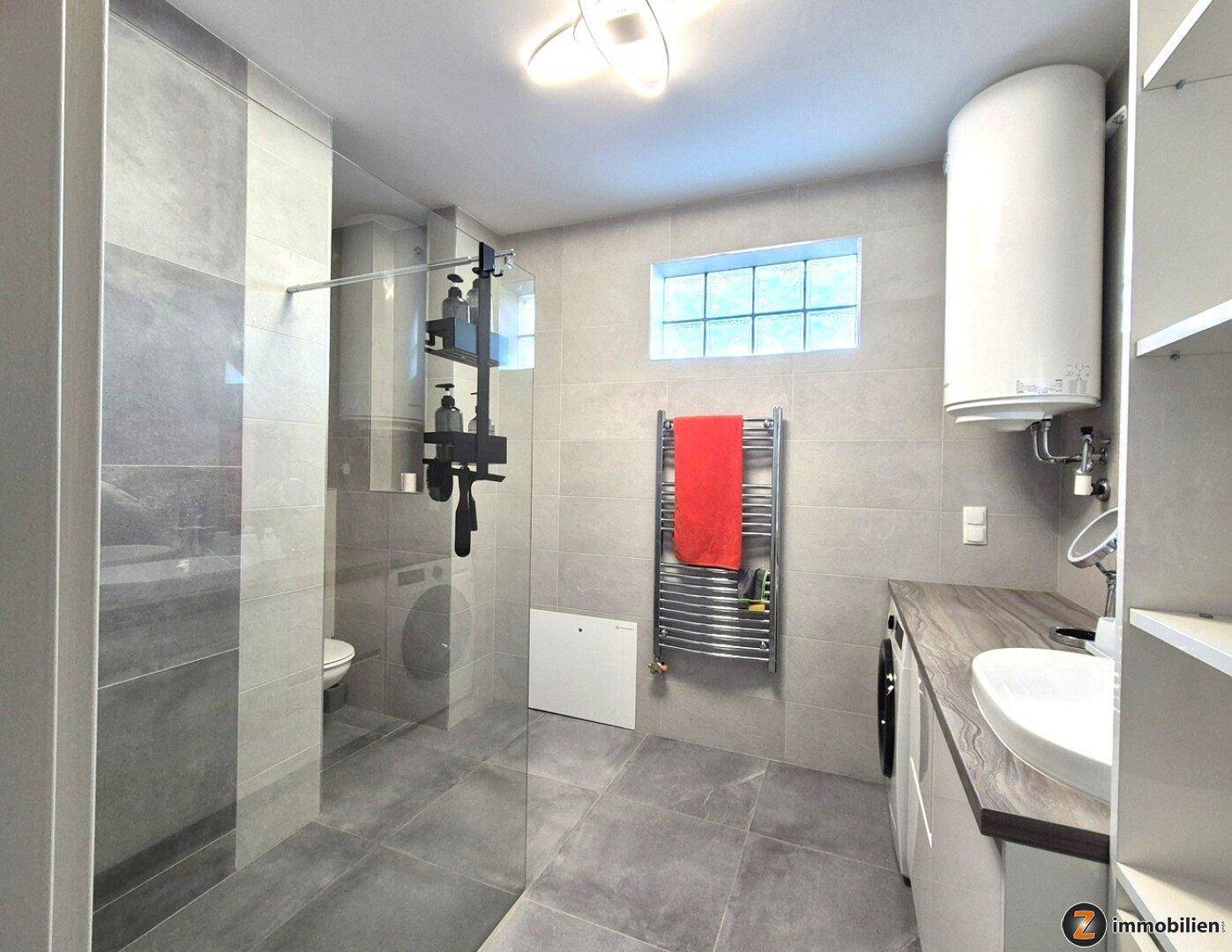 Helles Badezimmer mit großer begehbarer Dusche, beheiztem Handtuchhalter und Fenster.