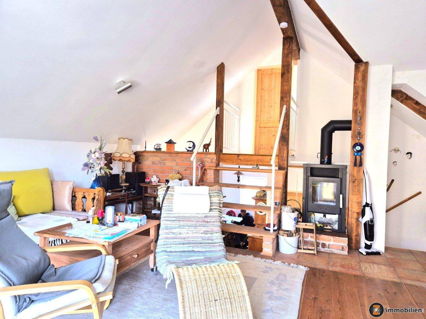 Wohnzimmer im Dachgeschoss mit Kaminofen, Holzbalken und rustikalem Charme.