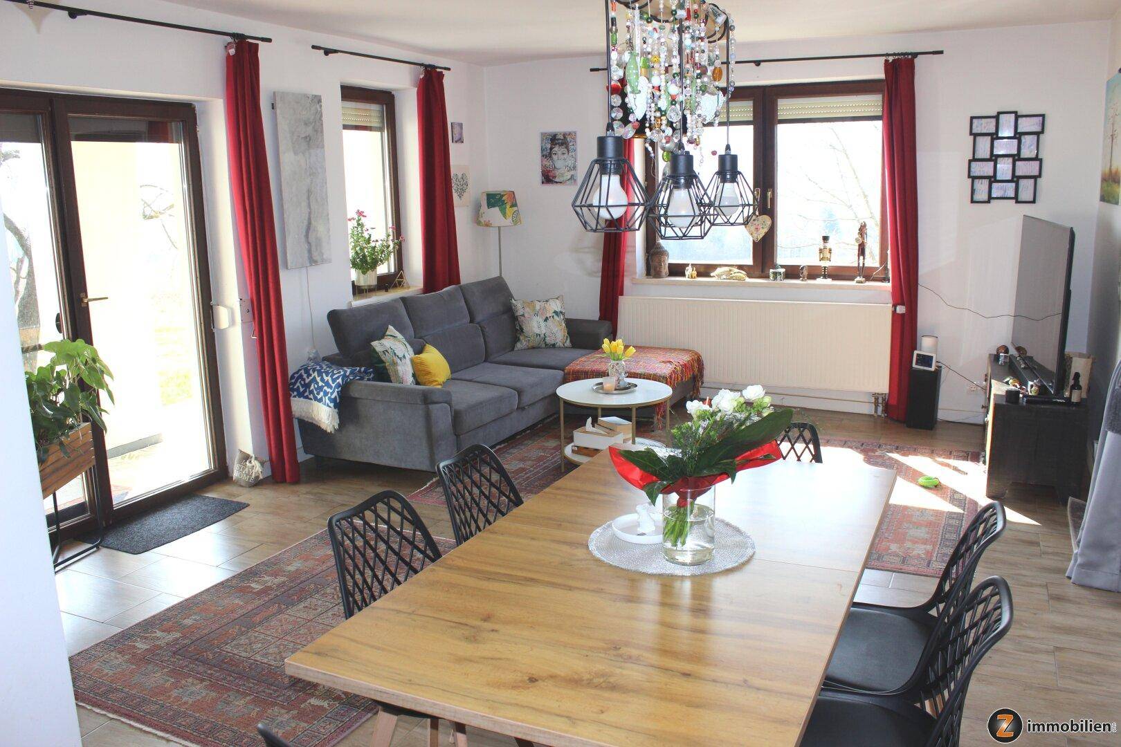 Heller Wohnbereich mit bequemer Couch, Esstisch und Zugang zu einem Außenbereich.