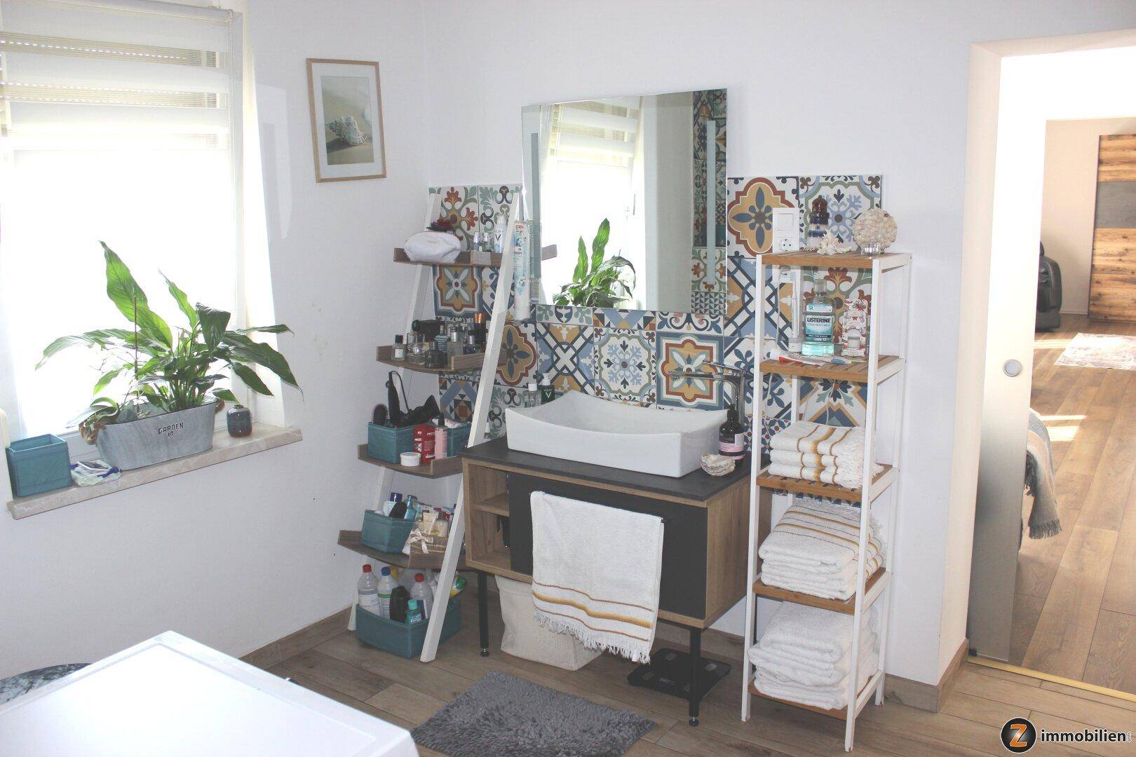 Badezimmer mit modernem Waschbecken, bunten Fliesen und Fenster für natürliches Licht.