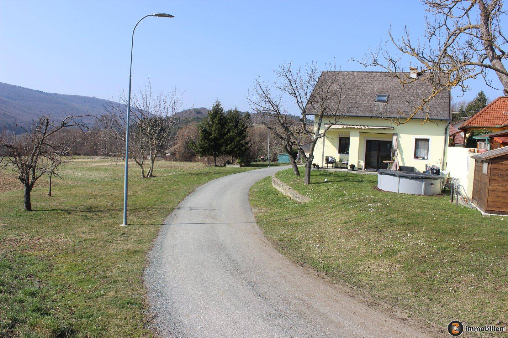 Rückansicht des Hauses mit Gartenbereich, kleinem Pool und ländlicher Umgebung.