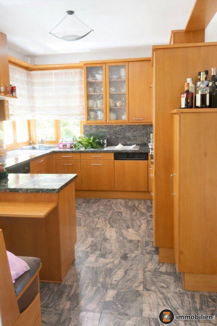 Helle Holzküche mit Granitarbeitsplatten, integrierten Geräten und Fenster mit Blick ins Grüne.