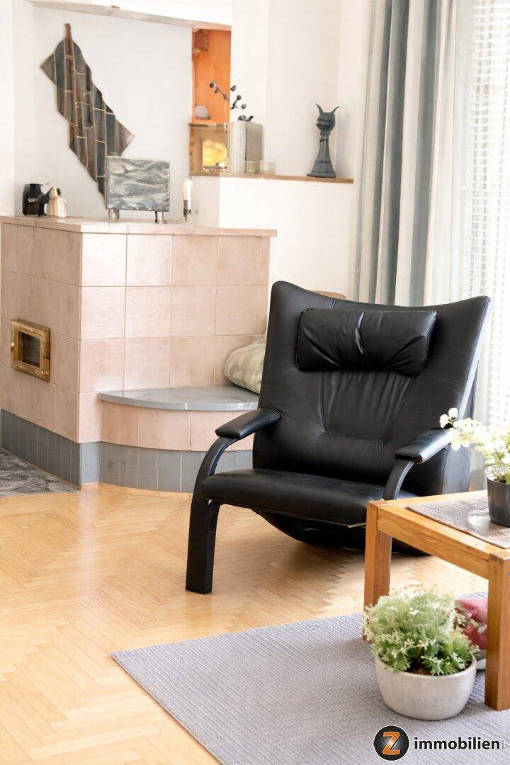 Gemütliche Sitzecke mit Kachelofen und bequemem Sessel, ideal zum Entspannen.