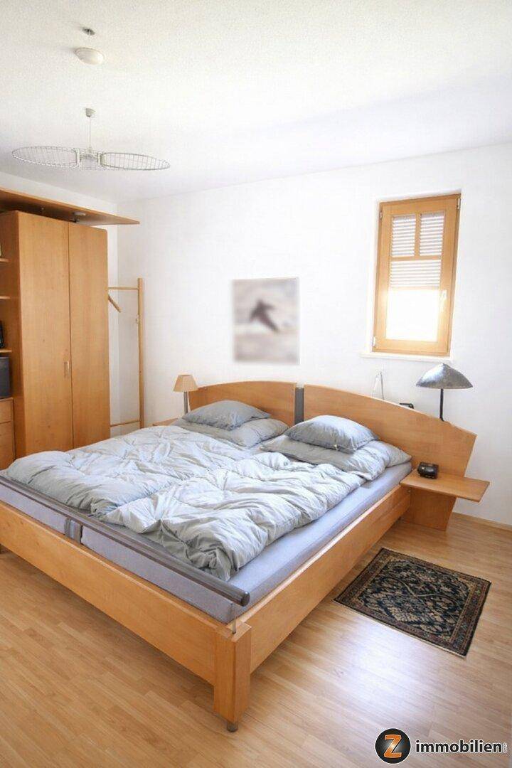 Helles Schlafzimmer mit Holzbett, Parkettboden und großem Kleiderschrank für Komfort.
