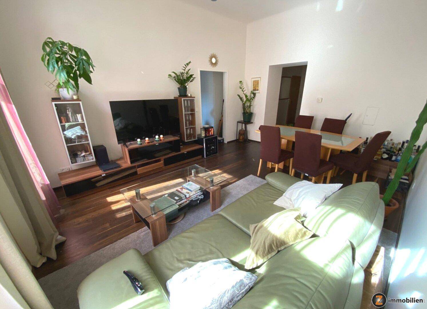 Geräumiger Wohn- und Essbereich mit bequemer Couch, großem Fernseher und Esstisch, ideal für geselliges Beisammensein.