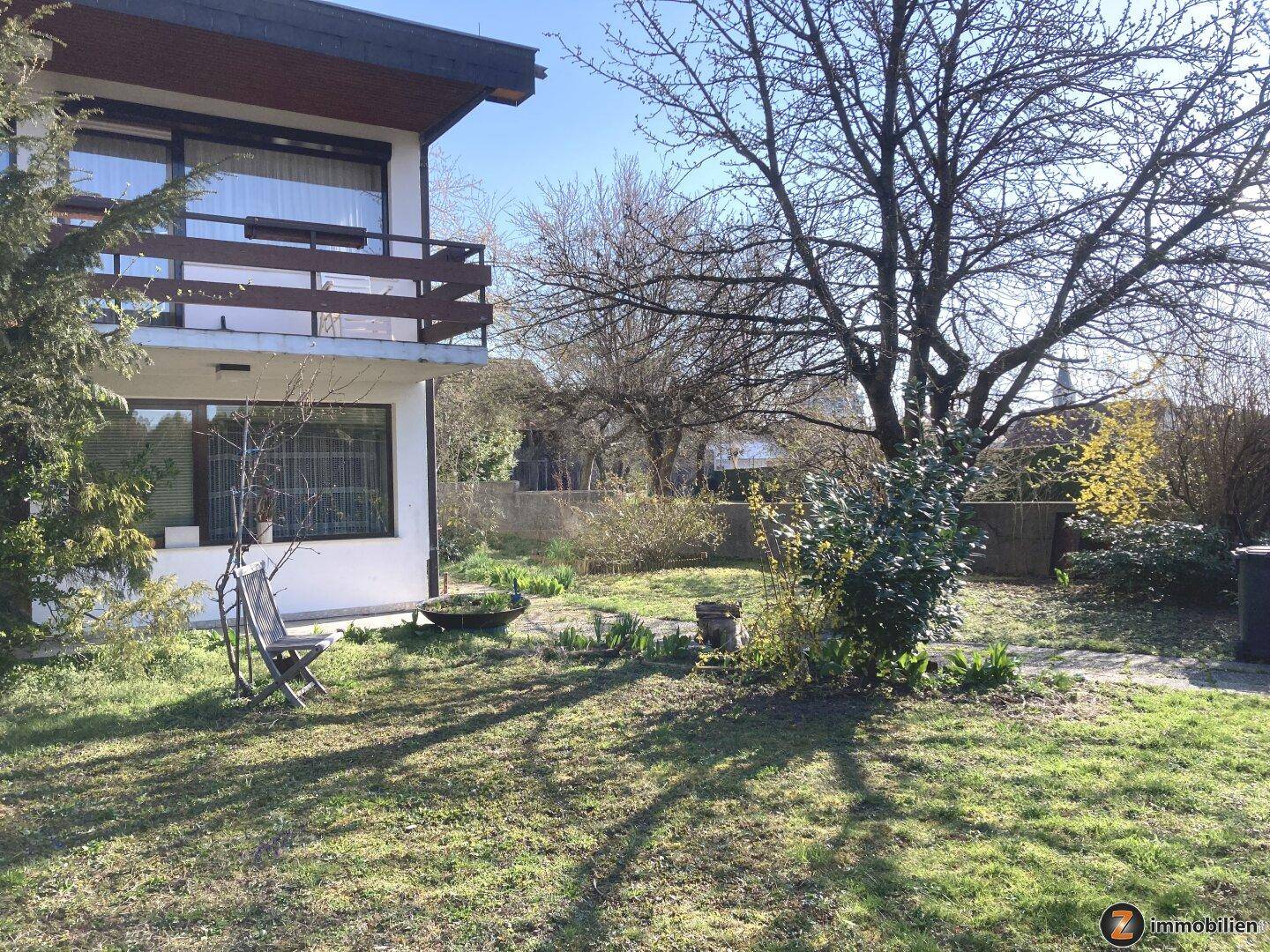 Großer Garten mit Rasenfläche, Bäumen und Blick auf die Hausfassade.