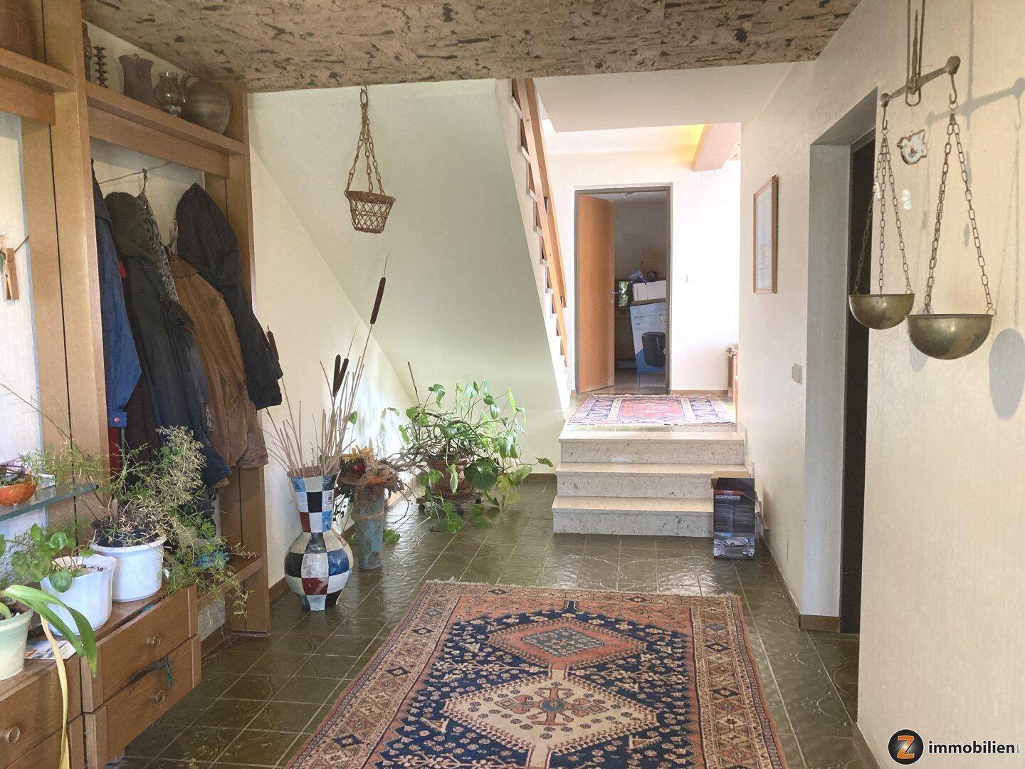 Geräumiger Eingangsbereich mit Fliesenboden, Garderobe und Treppe zum Obergeschoss.